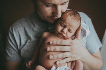 Ein Vater kuschelt sein neugeborenes Baby