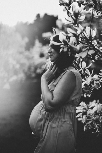 schwarz-weiß Bild einer schwangeren Frau zwischen Frühlingsblumen